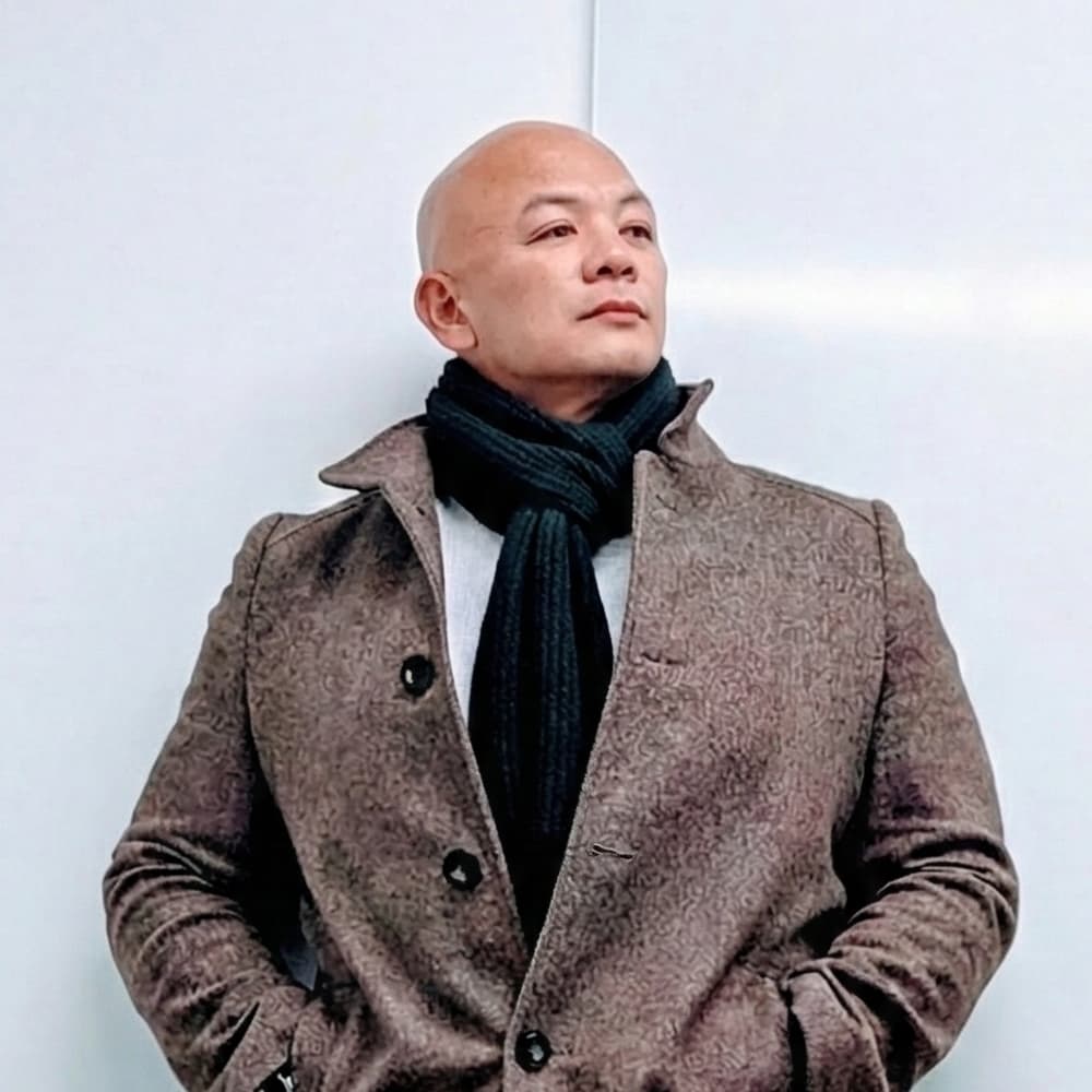 Portrait of Villar David in a coat and scarf, looking thoughtfully off-frame